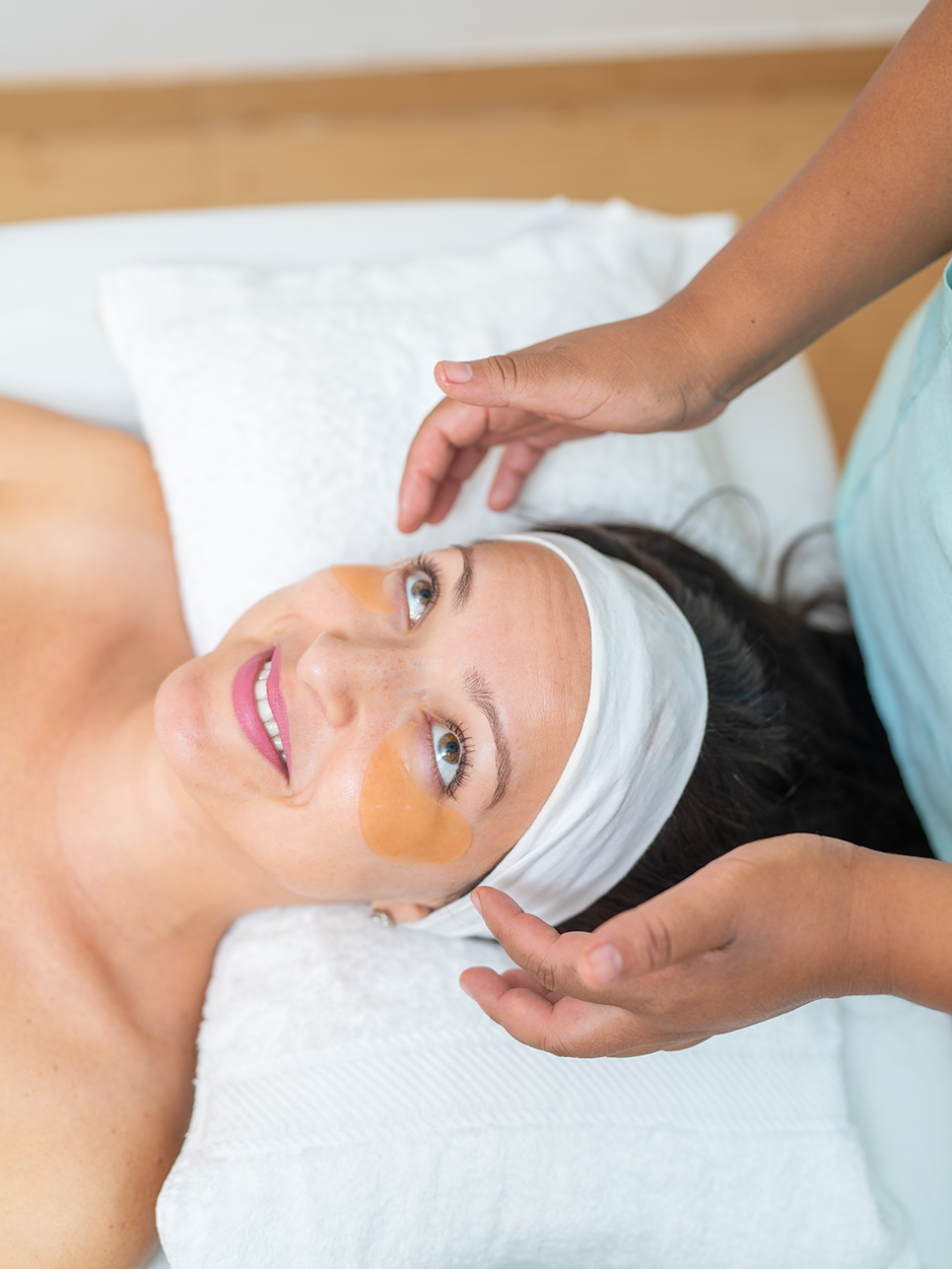 Spa worker applying anti dark circles patches on woman's face during beauty treatment in the spa